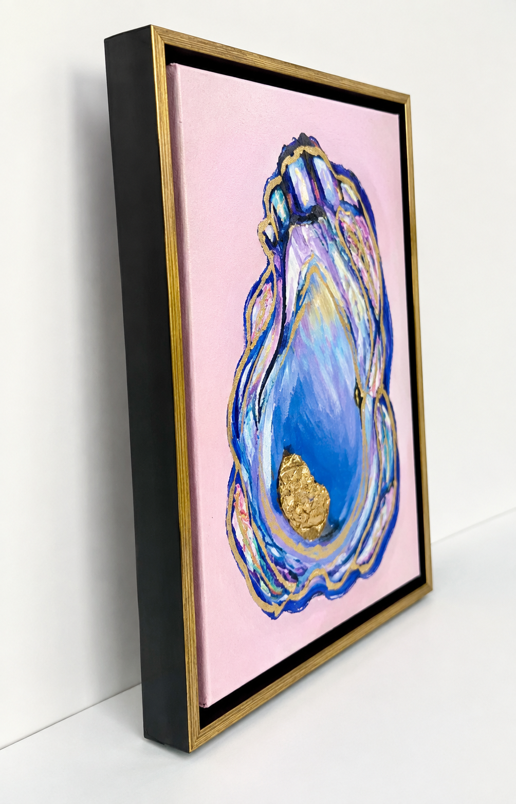 Original coastal oyster painting with layered blue and blush tones, metallic gold accents, and textured acrylic on canvas in a black and gold floater frame - side view.